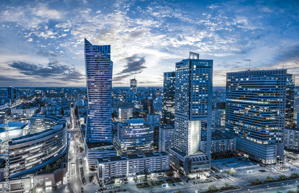 Panorama nocnych wieżowców Warszawy z Warsaw Spire w centrum, niebieska godzina z oświetlonymi oknami biurowców - obraz drukowany na płótnie