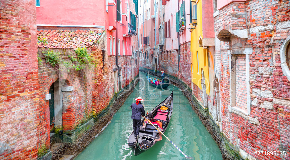 Venetian gondolier punting gondola through green canal waters of Venice Italy