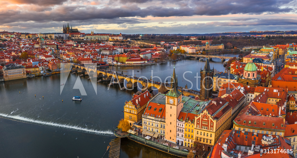 Fotoobraz Prague, Czech Republic - Aerial panoramic drone view of the world famous Charles Bridge (Karluv most) and St. Francis Of Assisi Church with a beautiful winter sunset. St. Vitus Cathedral at background beton architektoniczny