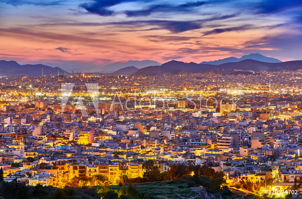 An evening cityscape of many buildings of Athens City, Greece. View from Filopappou Hill or Hill of the Muses. Colorful spring landscape. Urban skyscraper skyline rooftop view at night.