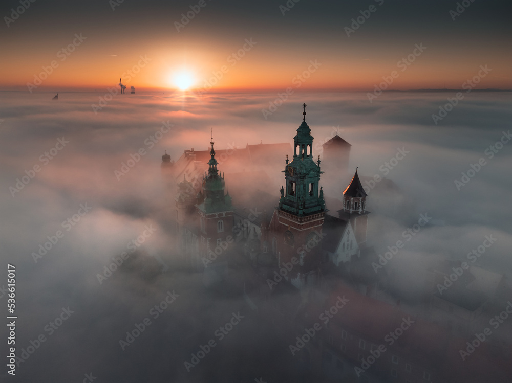 Wawel Castle in Kraków, Poland. Aerial, drone photo of the Royal Castle above the morning fog during the sunrise.