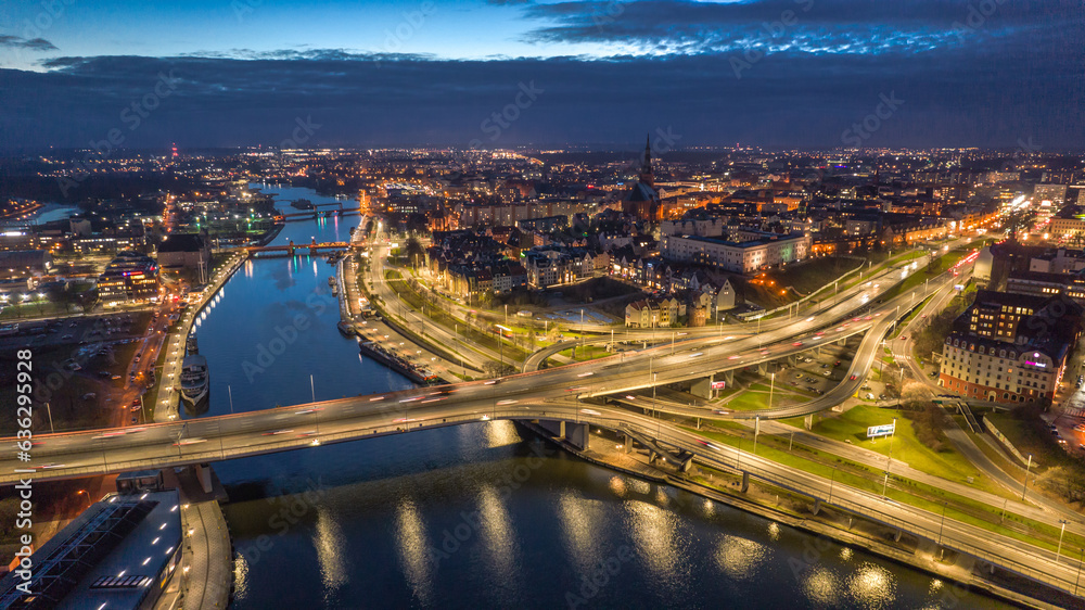 Nocna panorama Szczecina z lotu ptaka z Odrą, mostami, trasami komunikacyjnymi i rozświetlonym centrum miasta - obraz drukowany na płótnie