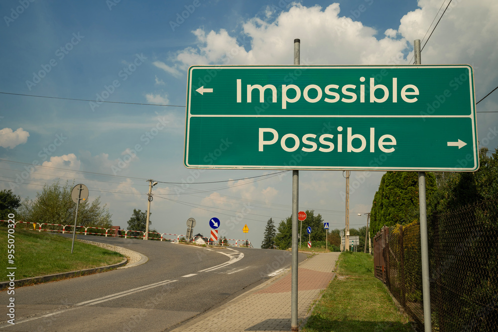 Drogowskaz z dwoma strzałkami pokazujący kierunki 'Impossible' i 'Possible' na zielonym znaku drogowym na tle błękitnego nieba z chmurami